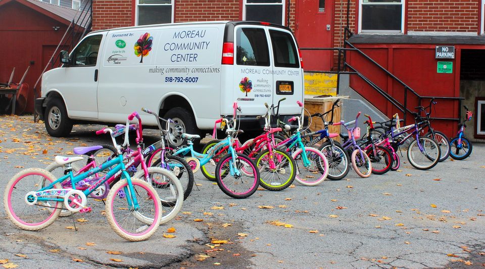 Row of children's bicycles in parking lot in front of white van.